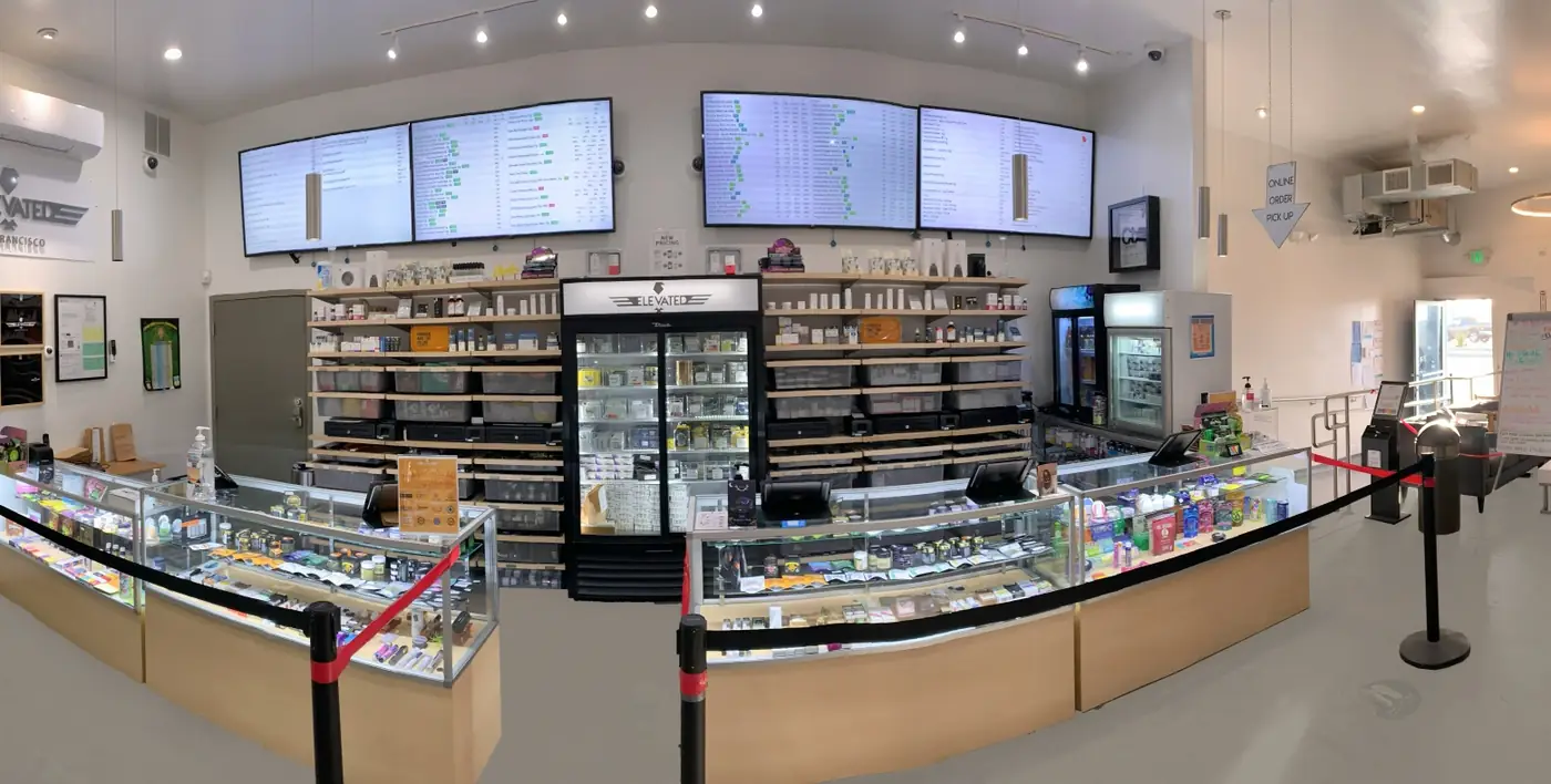 Inside Elevated San Francisco: glass display cases on pale wood counters, menu screens above, white walls